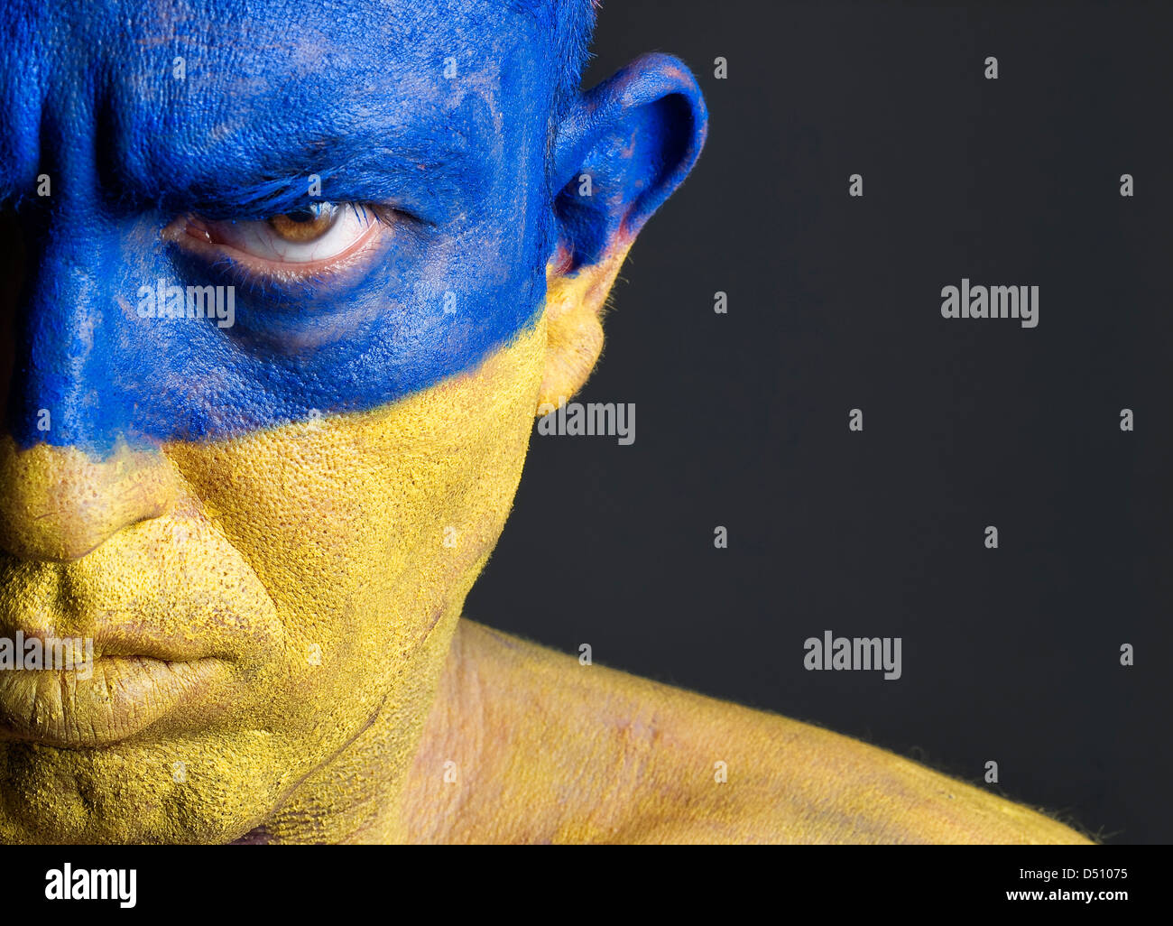 L'uomo con il suo volto dipinto con la bandiera dell'Ucraina. L'uomo è grave e composizione fotografica lascia solo metà della faccia Foto Stock
