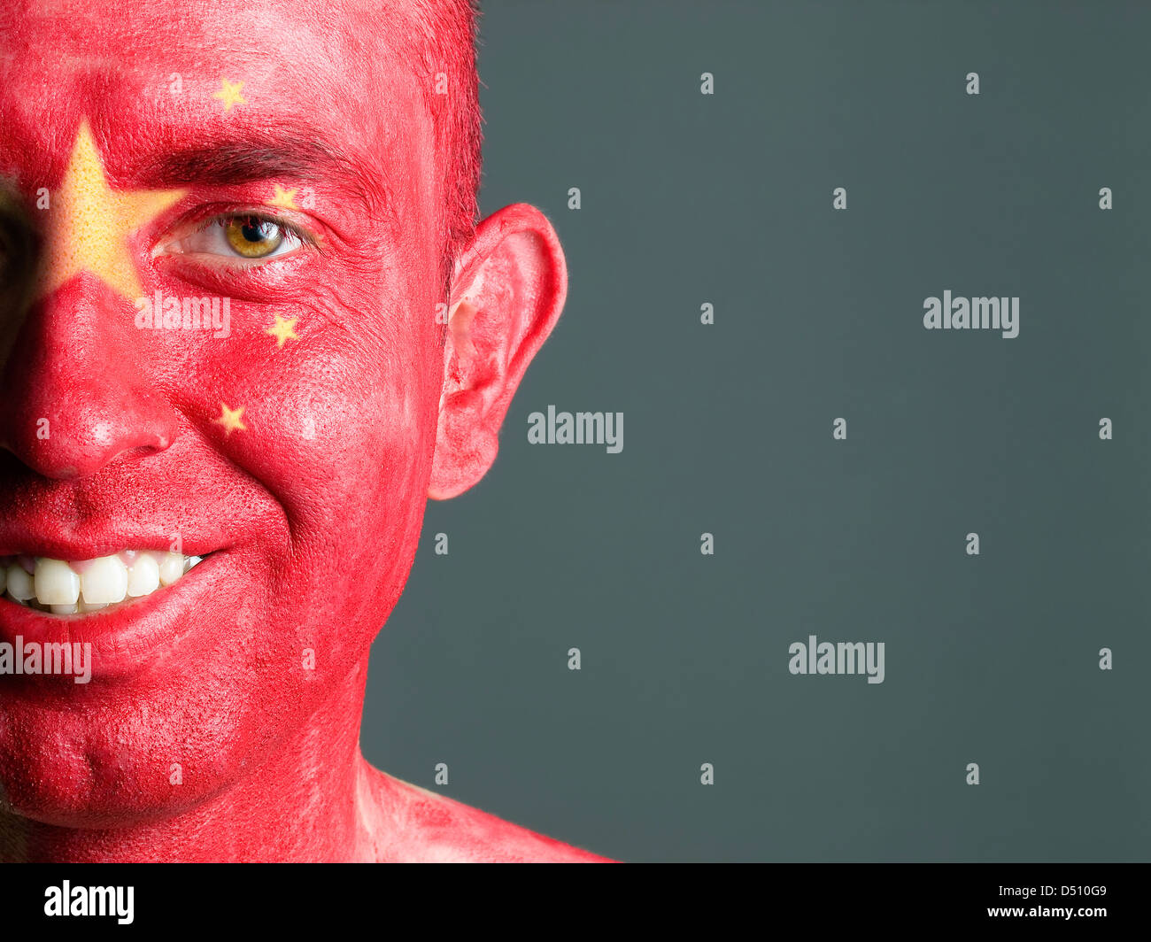 L'uomo con il suo volto dipinto con la bandiera della Cina. L'uomo è sempre sorridente e composizione fotografica lascia solo metà della faccia. Foto Stock