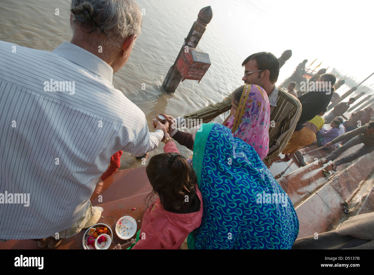 Una famiglia indù condividono una offerta rituale del latte al sacro fiume Yamuna a Vishram Ghat, Mathura, Uttar Pradesh, India Foto Stock