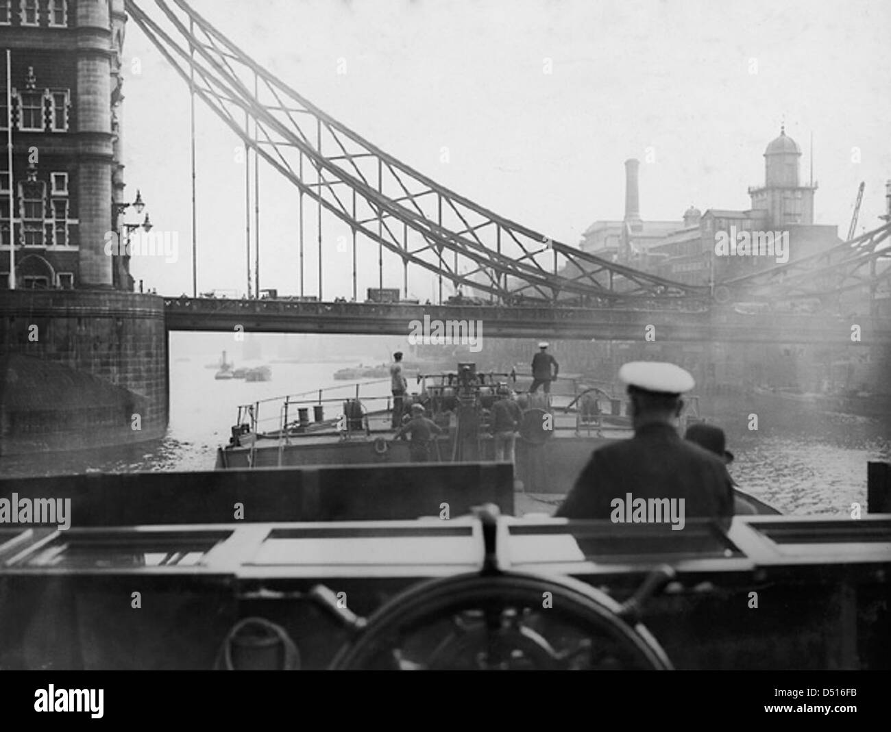 Questa fotografia storica mostra la SS "Ewell" che si avvicina all'iconico Tower Bridge di Londra. L'immagine evidenzia il passaggio della nave sotto il famoso ponte, un momento importante nella storia marittima. Foto Stock