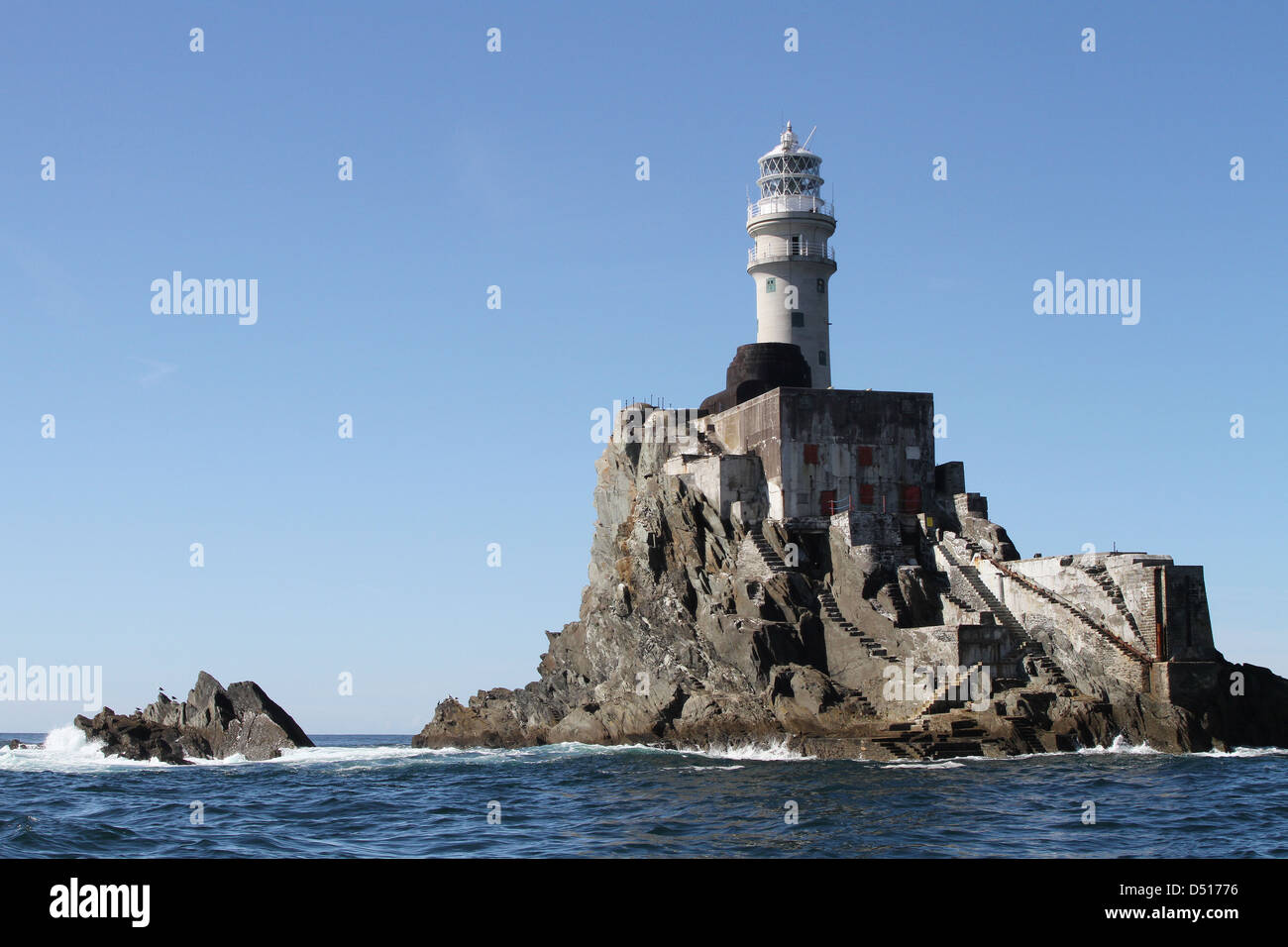 Faro di Fastnet, Fastnet Rock, County Cork, Irlanda ha sparato dalla barca nella soleggiata giornata autunnale con cielo blu e resti di vecchia base torre Fastnet visibile. Foto Stock