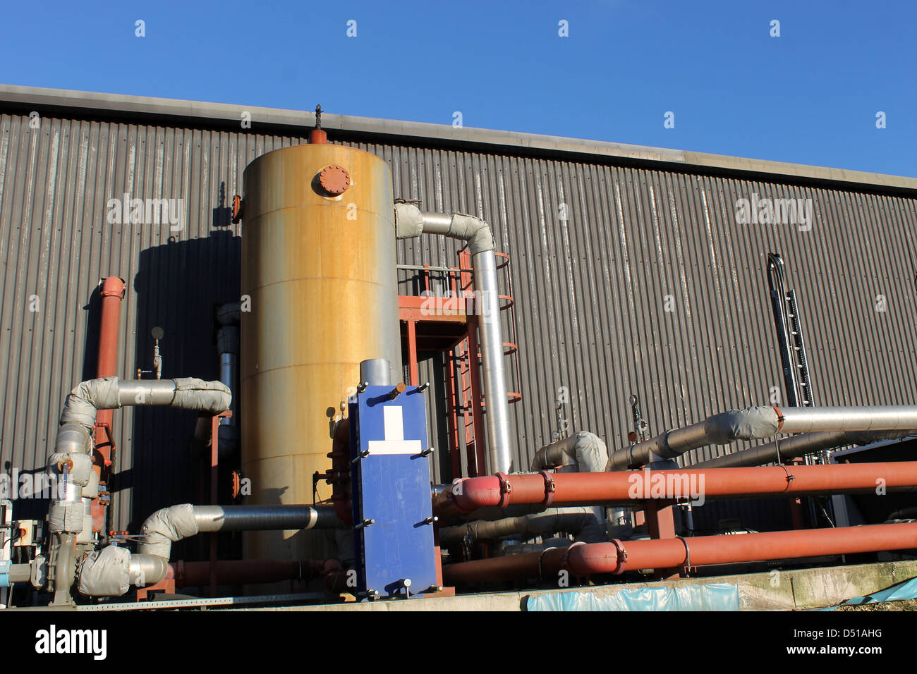 Esterno del moderno edificio industriale con le tubazioni e il serbatoio. Foto Stock