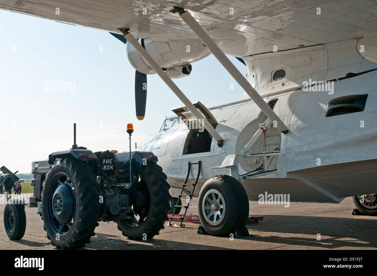 Un bianco storica 'flying boat' aeromobile siede sulla pista di un aeroporto, con rimorchiare il trattore parcheggiato lungo il lato. Foto Stock