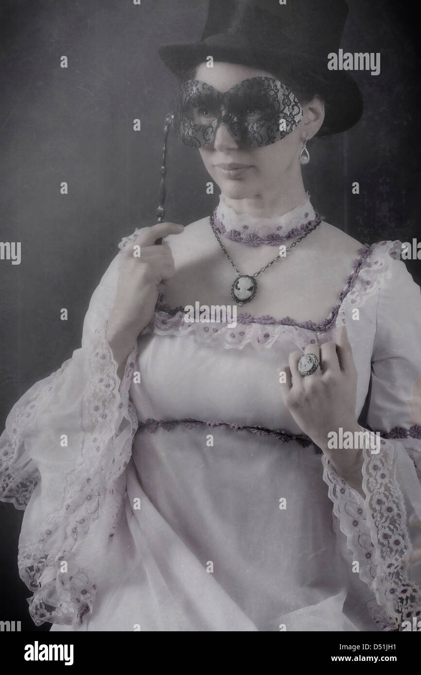 Una donna in un periodo vestito con un cappello a cilindro e una maschera nera Foto Stock