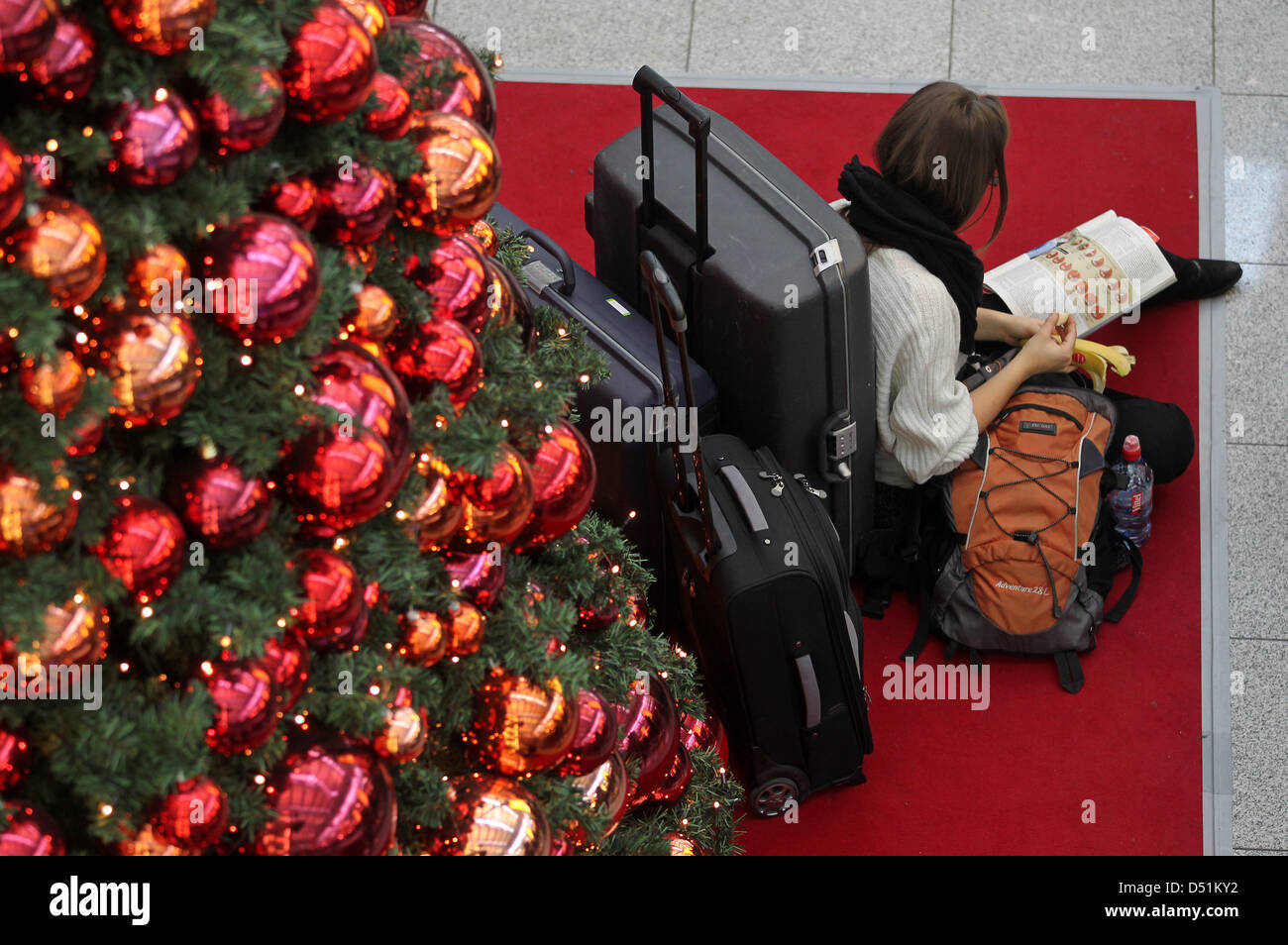 Eine Reisewillige hat es sich am Freitag (24.12.2010) auf dem Düsseldorfer Flughafen in der neben Abfertigungshalle einem Weihnachtsbaum bequem gemacht. Der Flughafen hat wegen des heftigen Schneefalls seinen Betrieb bis zum späten Vormittag eingestellt. Foto: Roland Weihrauch dpa/lnw Foto Stock