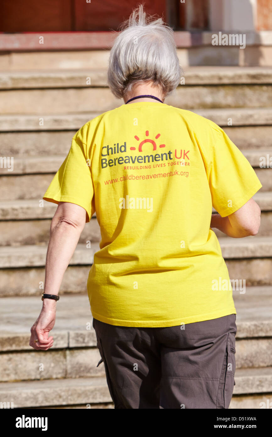 Una donna è visto indossare un giallo t-shirt con il logo della carità bambino lutti UK durante una visita reale Foto Stock