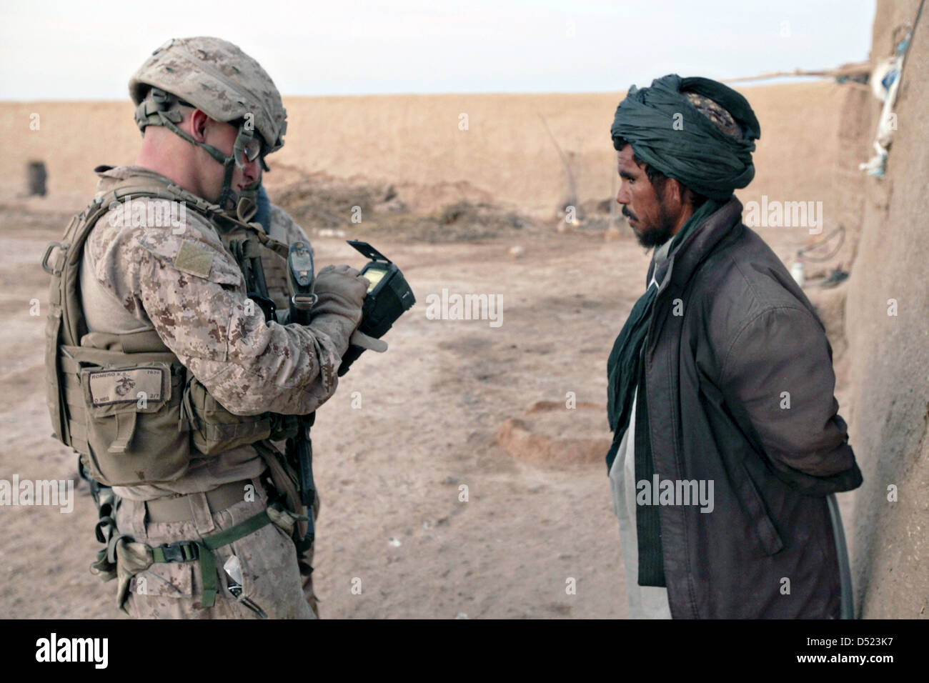 Un marine statunitense utilizza il Secure Electronic Enrollment Kit per registrare un uomo afghano dopo la scansione di un composto durante una pattuglia Marzo 15, 2013 in Boldak, Afghanistan. Foto Stock