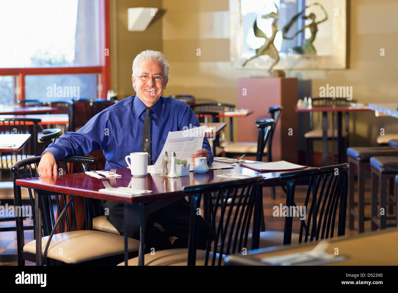 Cafe ispanica proprietario seduta a tavola Foto Stock