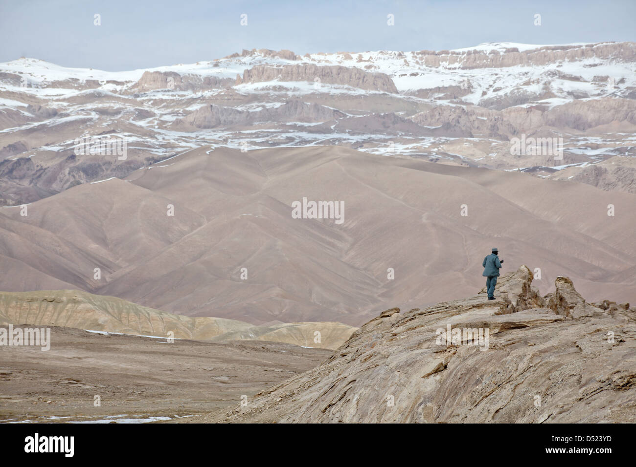 Una polizia nazionale afgana officer fornisce la sicurezza sulla cima di una collina che domina una valle Marzo 11, 2013 in provincia di Bamiyan, Afghanistan. Foto Stock