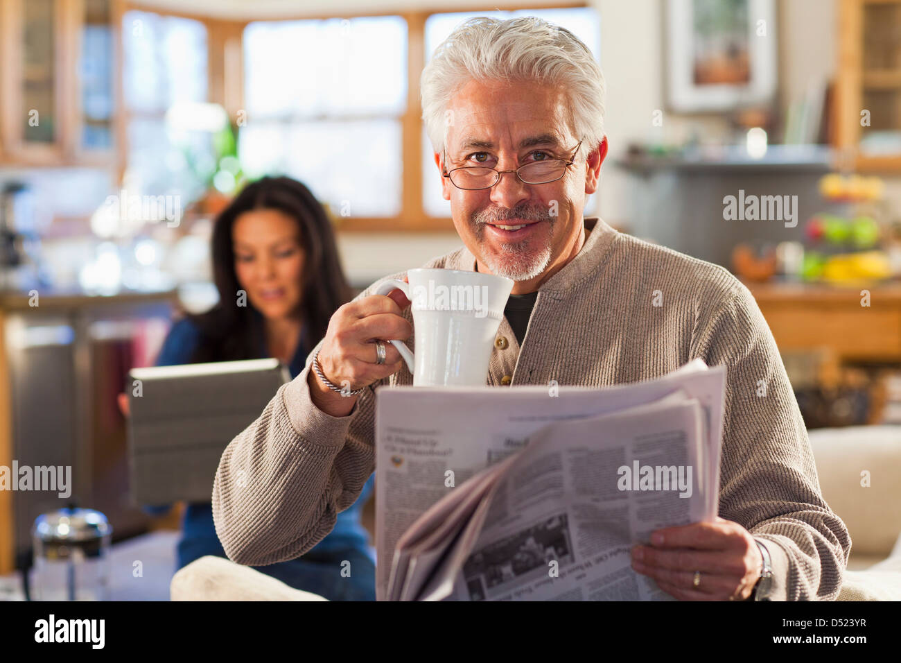 Uomo ispanico a bere caffè e quotidiano di lettura Foto Stock