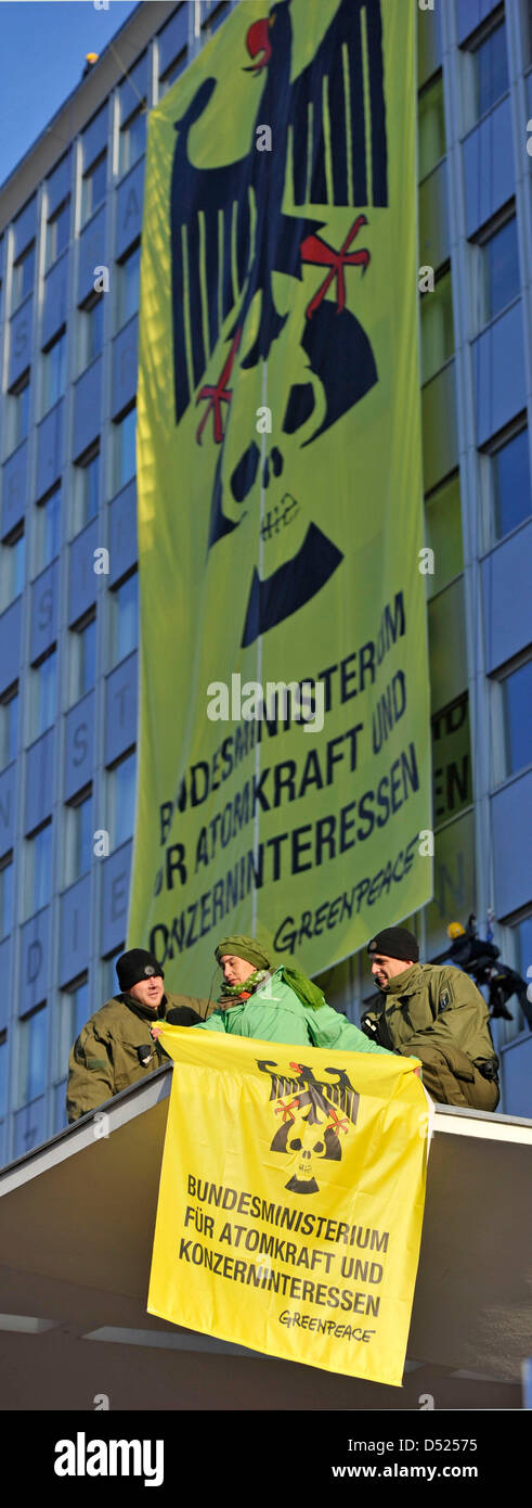 Poliziotti di rimuovere un attivista di Greenpeace da un tetto dell'ambiente federale ministero a Berlino (Germania), 18 ottobre 2010. Gli alpinisti della protezione ambientale organizzazione attaccato un banner di lettura "Ministero Federale per l'energia nucleare e companys' lobby e'. Greenpeace protesta contro l'esplorazione della miniera di Gorleben come un deposito per le scorie nucleari che è stato ripreso aga Foto Stock