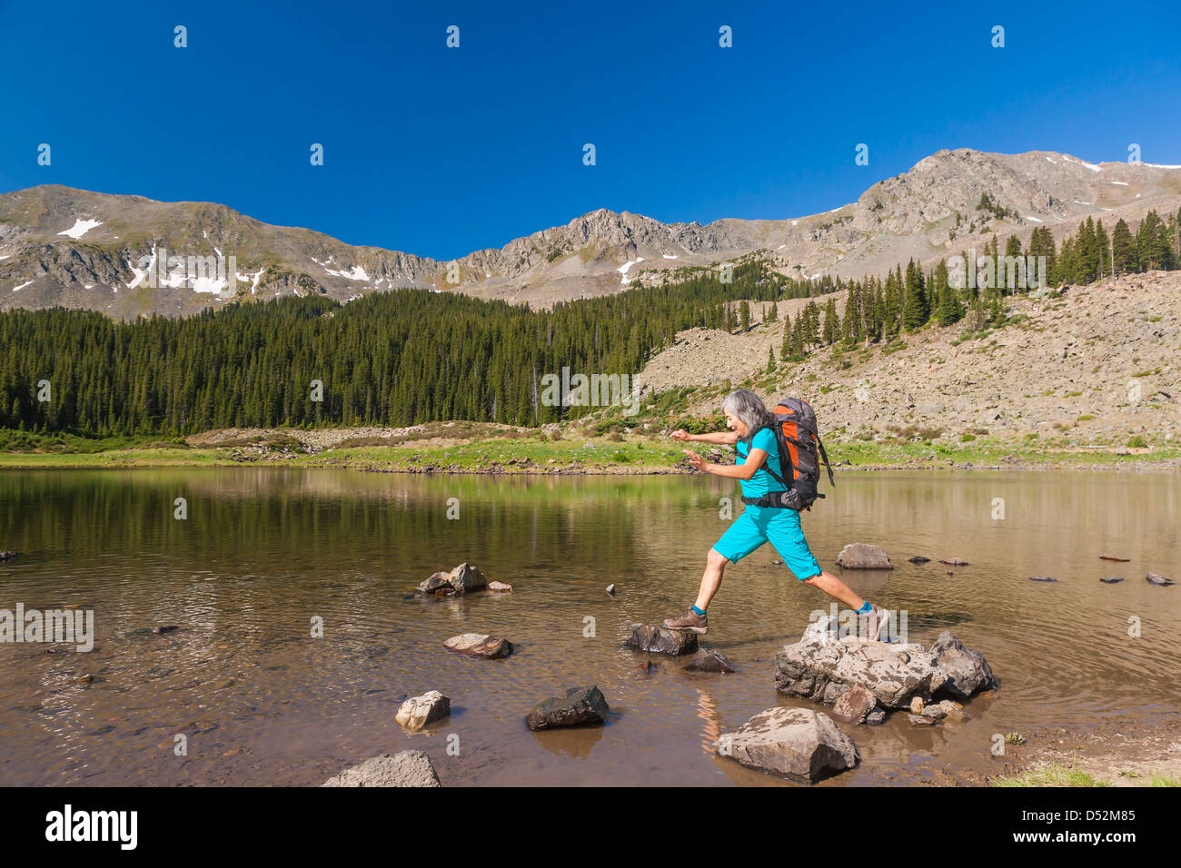 Escursionista ispanica arrampicata sulle rocce nel lago Foto Stock