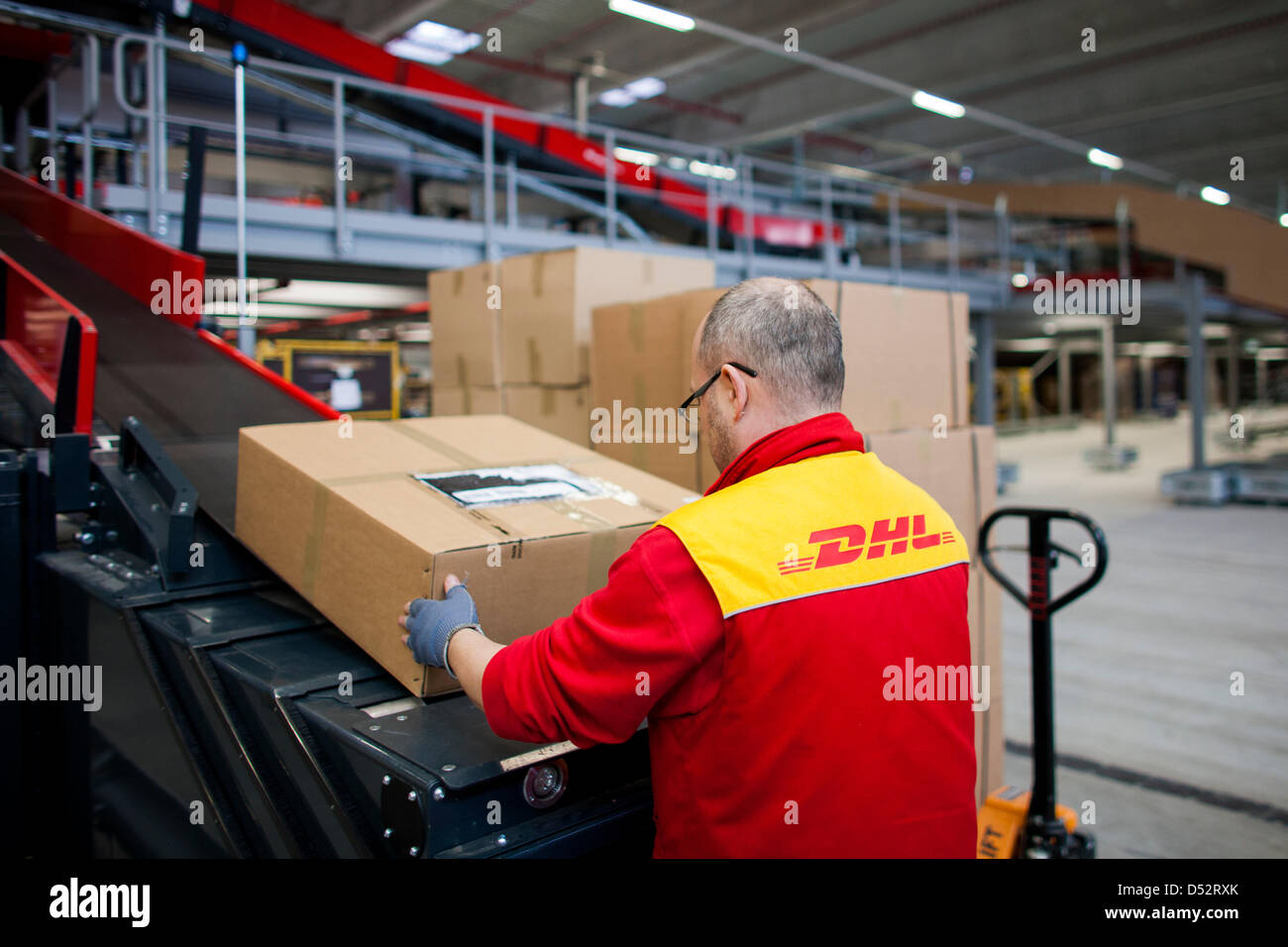 Un dipendente di Deutsche Post DHL mette un pacchetto sulla linea di montaggio in corrispondenza del primo meccanica del punto di consegna a Bochum, Germania, 20 marzo 2013. È il secondo sistema nazionale che legge i pacchetti automaticamente e li distribuisce al trasportatore. Foto: Rolf Vennenbernd Foto Stock