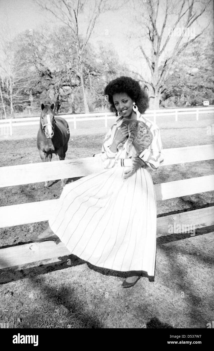 Una modella si trova su una recinzione a Tallahassee, Florida, con un gatto arroccato nelle vicinanze. Questo ritratto, realizzato negli anni '1930, cattura sia la moda della modella che lo stile di vita rilassato nella capitale della Florida durante l'epoca. Foto Stock