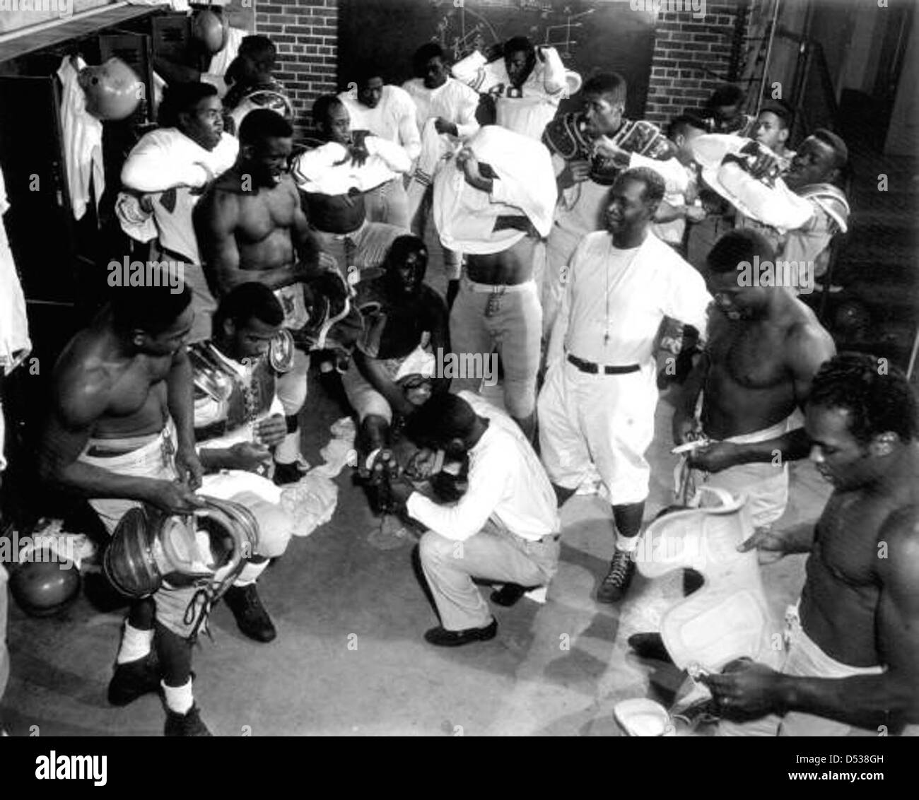 Il coach Alonzo 'Jake' Gaither sta con la squadra di football della Florida Agricultural and Mechanical University (FAMU) nel loro spogliatoio. Gaither, un rinomato allenatore di football afroamericano, ha contribuito a plasmare il programma di football della FAMU. Foto Stock
