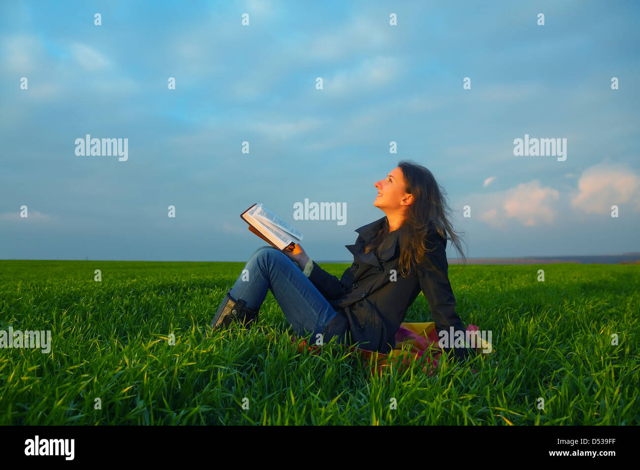 Teen girl leggendo la Bibbia seduti all'aperto al tramonto Foto Stock