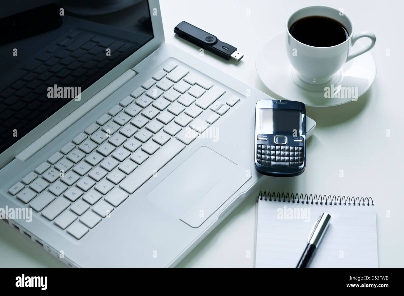Laptop moderno con telefono cellulare, una tazza di caffè, il blocco note e penna stilografica e pendrive usb Foto Stock