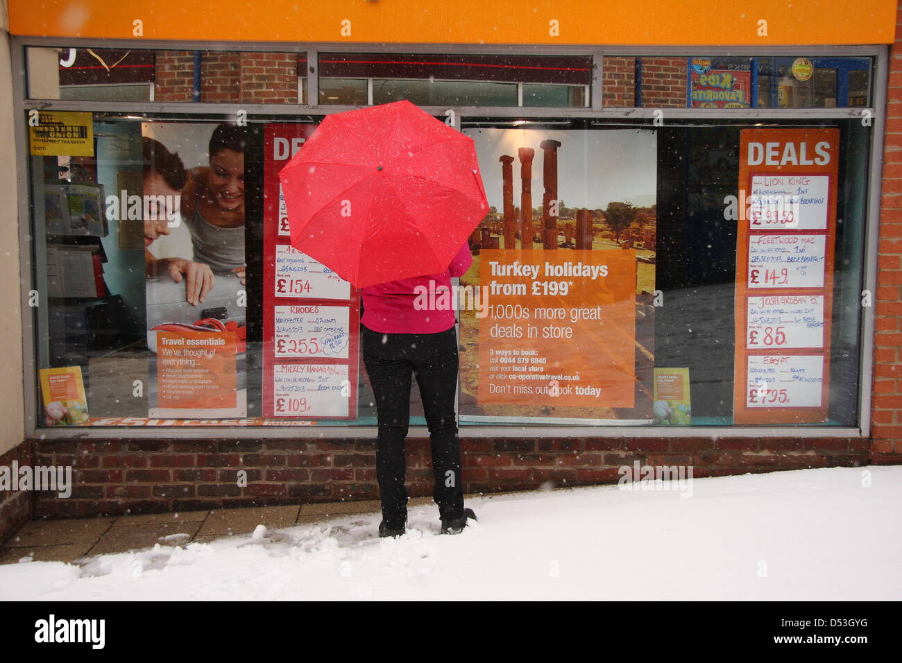 Shopper sogni di climi più soleggiato al travel agent finestra della molla durante la tempesta di neve, Regno Unito, Foto Stock