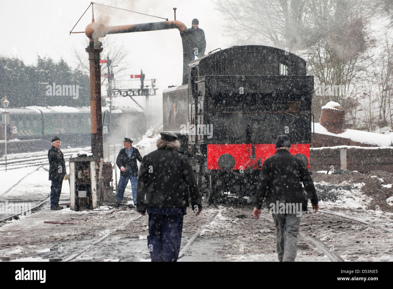 Bridgnorth, Shropshire, Regno Unito. Il 23 marzo 2013. La Severn Valley Railway 'Spring vapore Gala " weekend è influenzata dal clima invernale. In una tempesta di neve un motore a vapore viene rabboccato con acqua dall'acqua vintage bowser a Bridgnorth depot. Credito: John Bentley / Alamy Live News Foto Stock