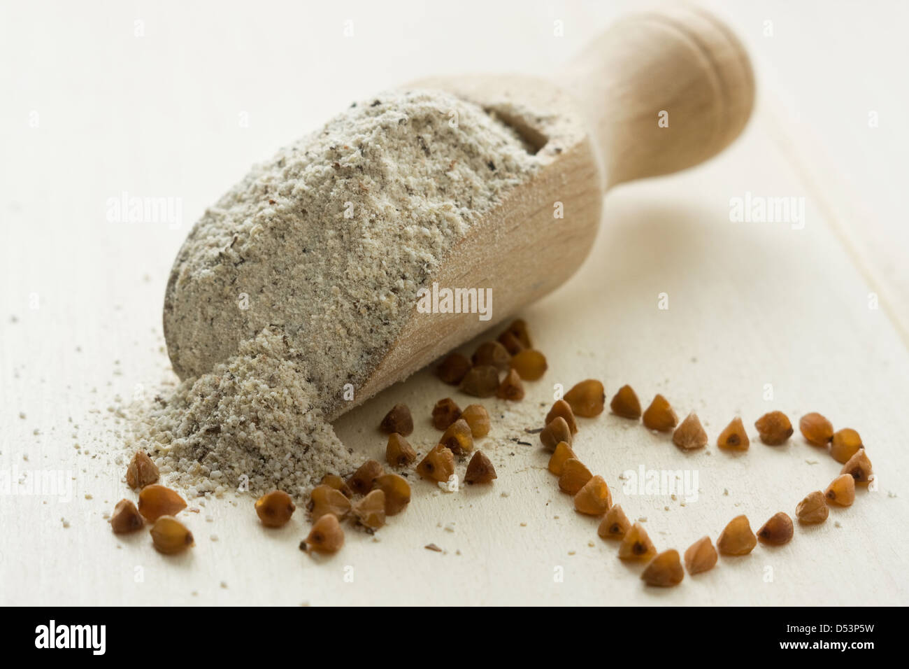 Farina di grano saraceno in cucchiaio di legno. Cereali di grano saraceno e forma di cuore Foto Stock