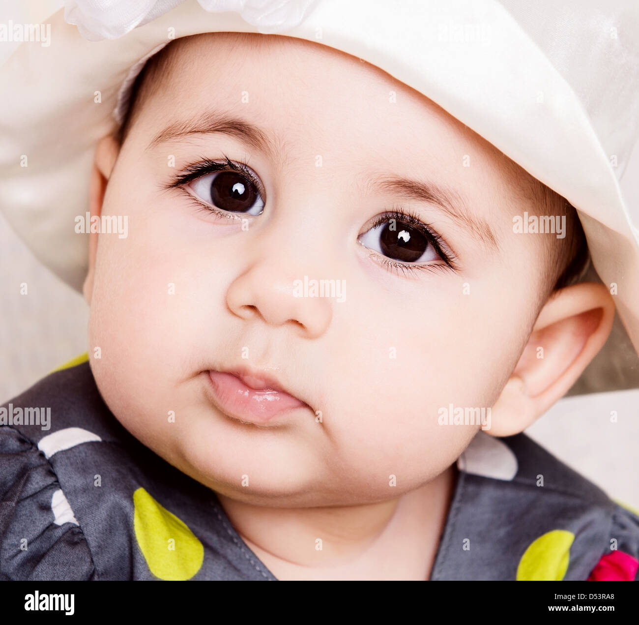 Carino Baby girl in abito punteggiata in eleganti hat Foto Stock