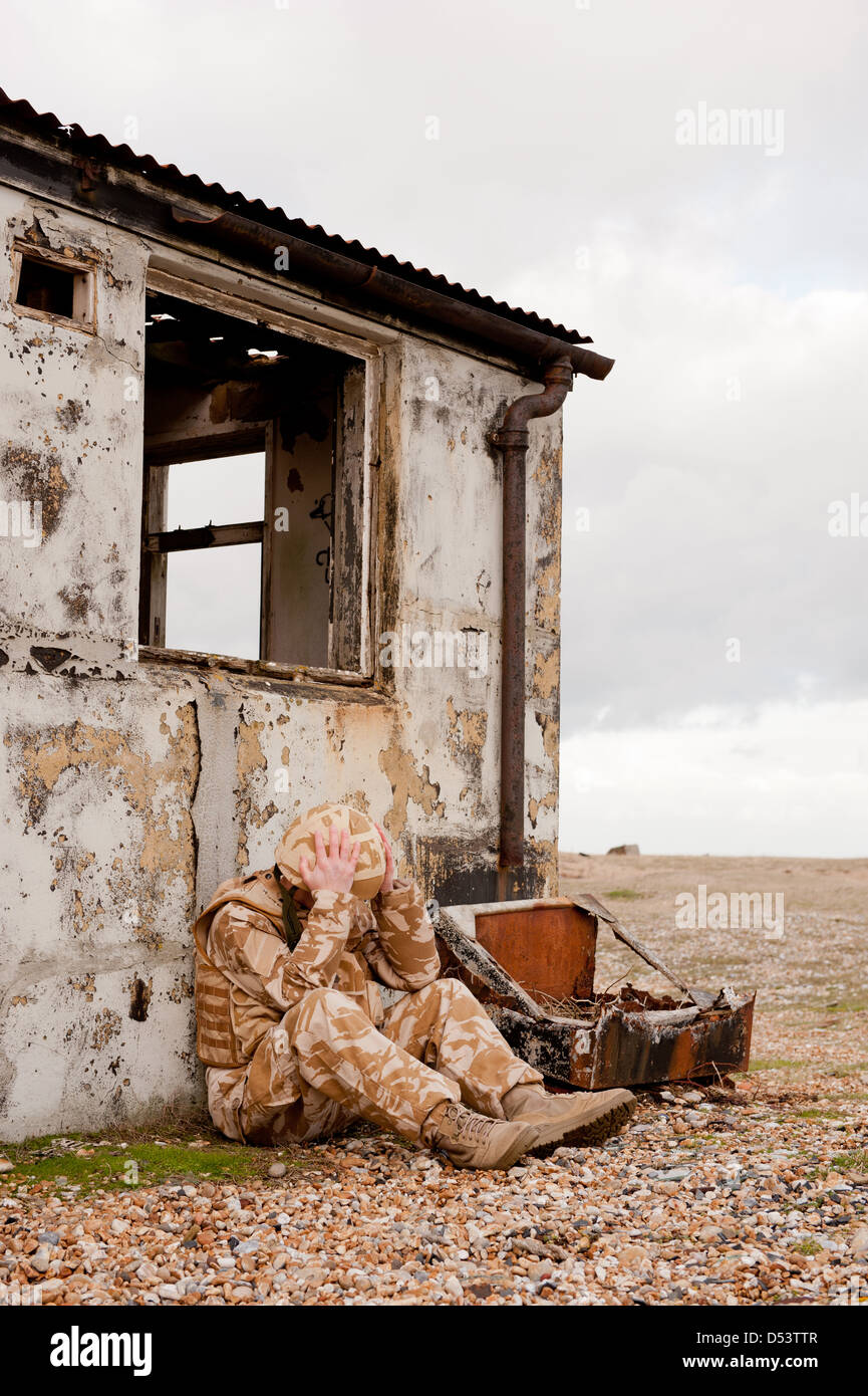 Soldato sofferenza con proprio Disturbo Post-traumatico da Stress sul campo di battaglia. Soldato indossa militare britannico uniforme del deserto. Foto Stock