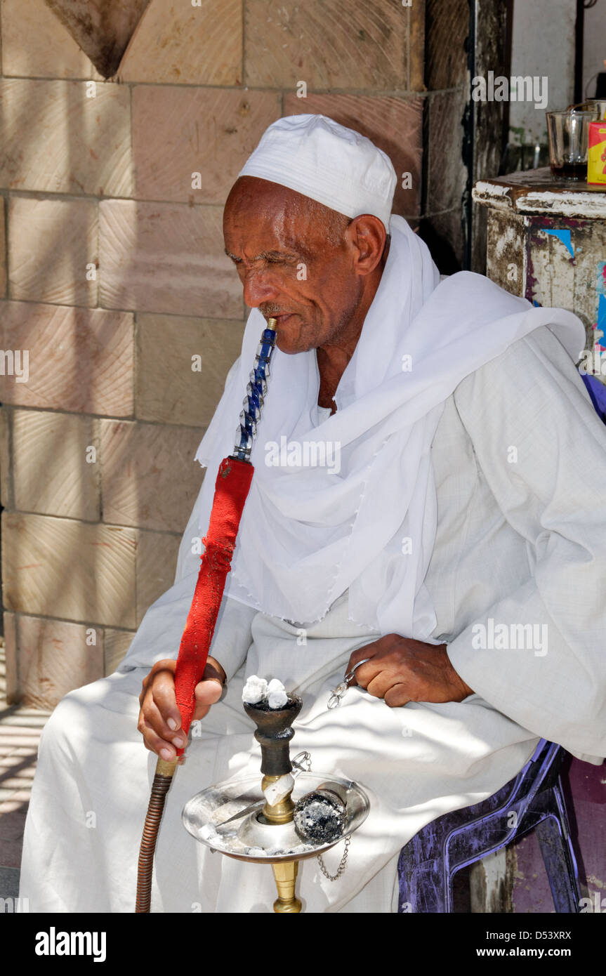 Aswan. L'Egitto. Vista di un uomo di fumare un tubo di acqua (hookah o Shisha) in Aswan il souq. Foto Stock