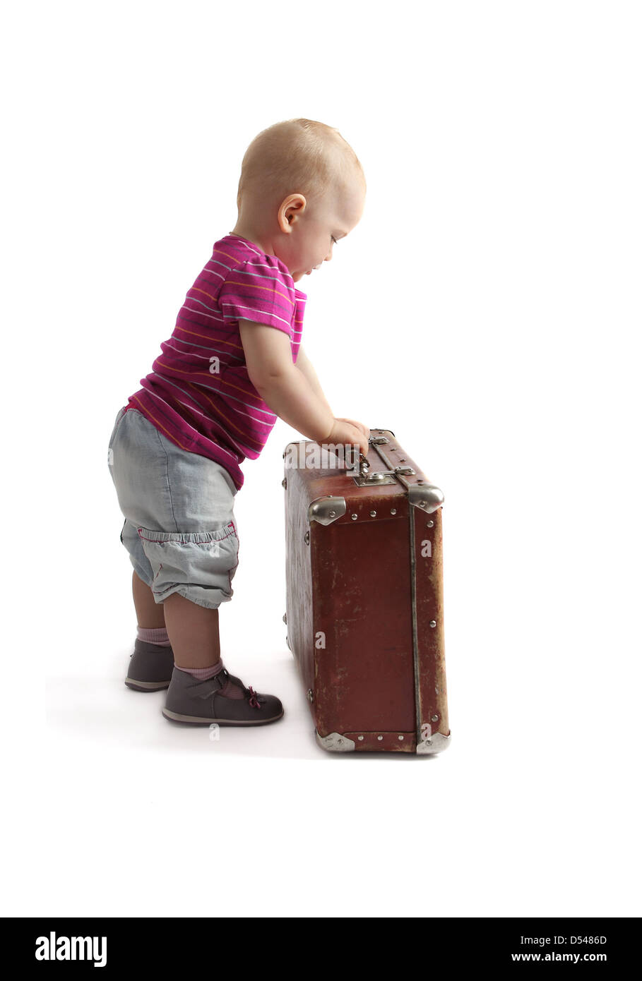 Piccolo bambino in piedi accanto ad una valigia, sfondo bianco, isolato Foto Stock