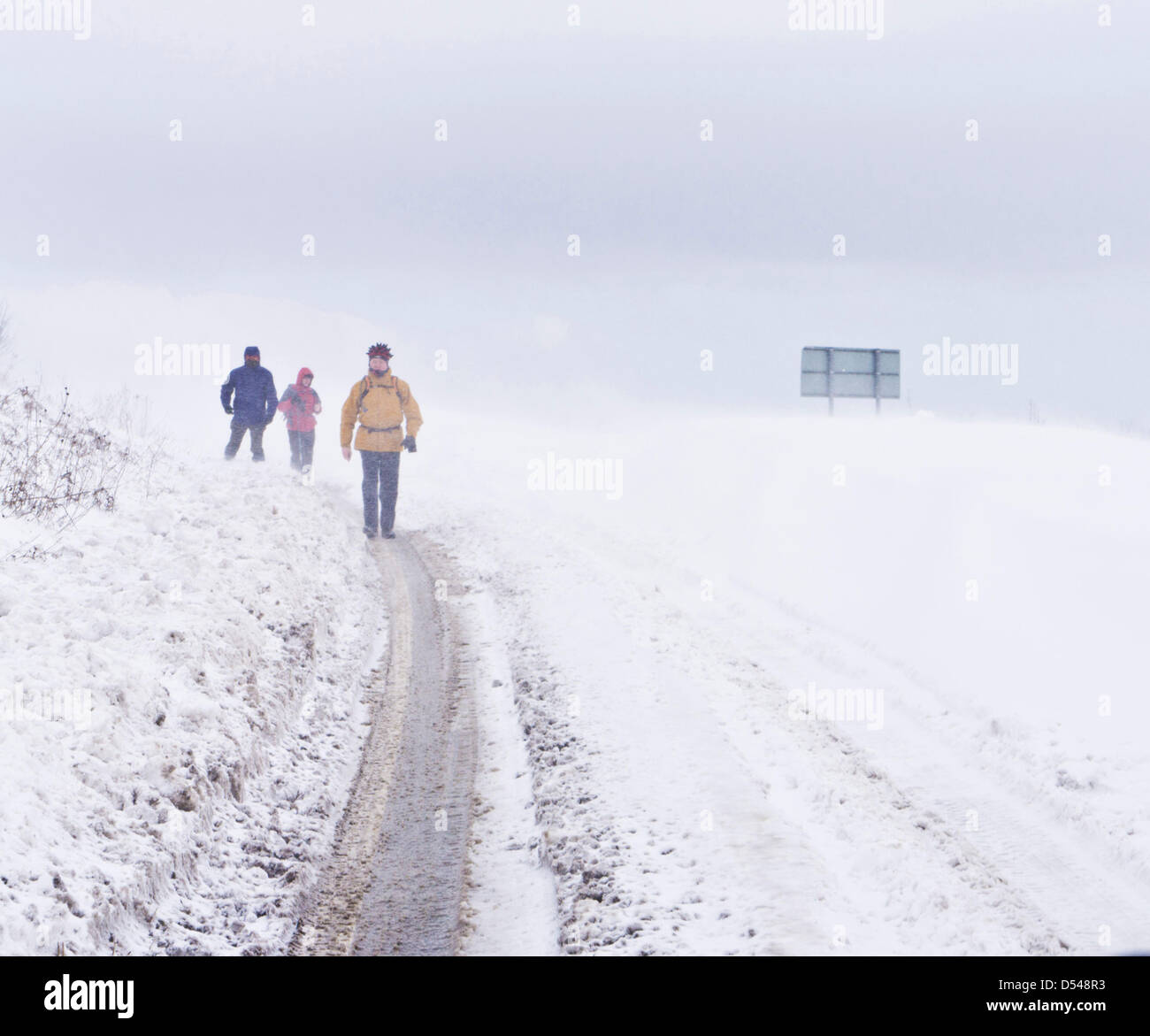 Inglese Peak District, Derbyshire, Regno Unito. Il 24 marzo 2013. Gli escursionisti a piedi accanto alla A621 tra Baslow e Sheffield che è coperto di neve. Neve pesante e alta venti erano causando la tempesta di neve a bloccare la strada. Credito: occhio35/Alamy Live News Foto Stock