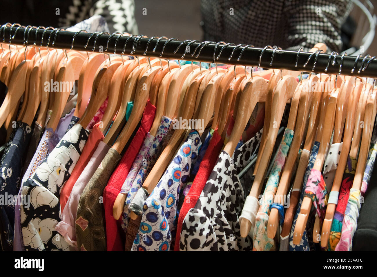 Pulite e ordinate fila di seconda mano abiti vintage in legno appendiabiti su una rampa di vestiti in un vintage fair Foto Stock