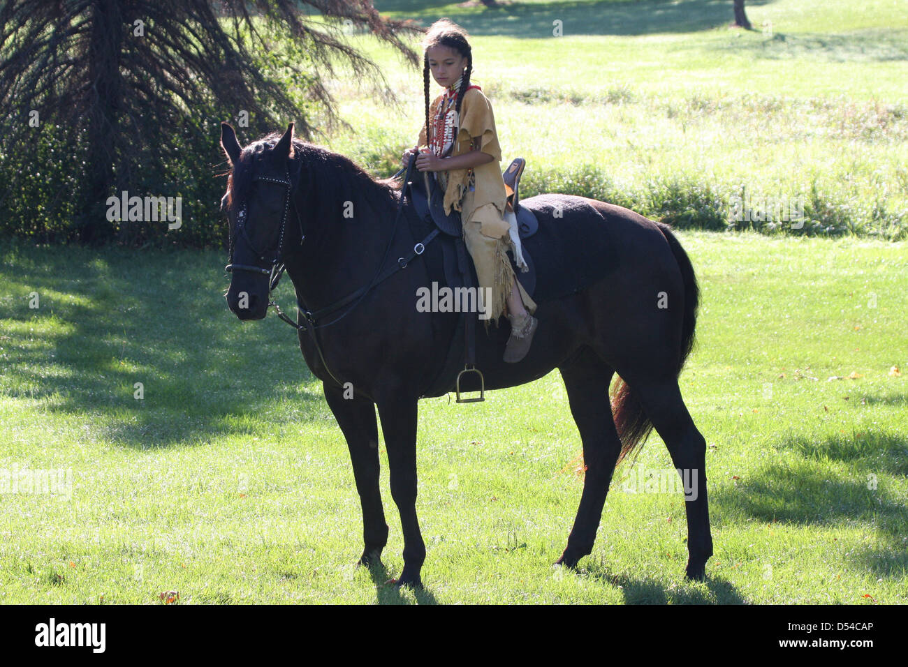 Un giovane nativo americana Indiani Sioux Lakota boy in sella ad un cavallo nero Foto Stock