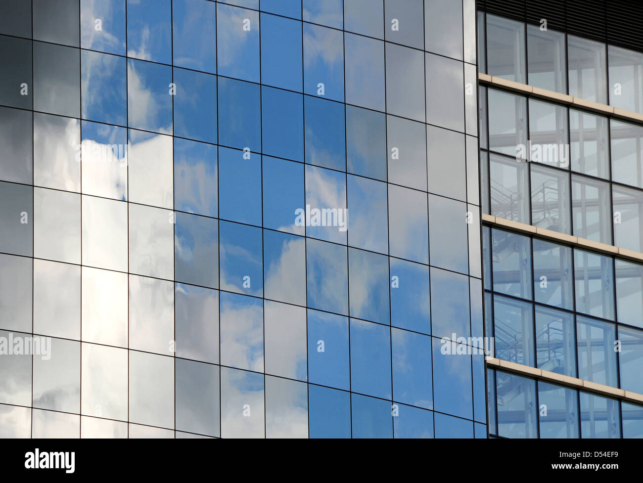 Windows riflettente sul lato di un ufficio moderno edificio con le nuvole e il cielo Foto Stock