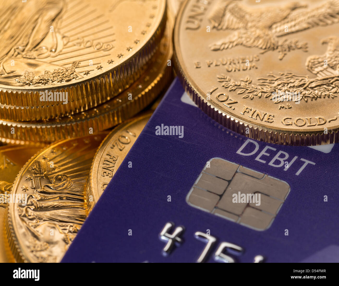 Oro massiccio monete in contrasto con la parola di addebito sulla plastica carta di credito suggerendo problemi di debito Foto Stock