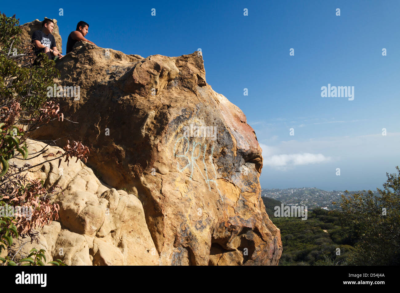 Gli escursionisti in cima a formazione di roccia dal cranio roccia sopra il Temescal Trail Ridge vedere l'Oceano Pacifico e viste sulla città di distanza Foto Stock