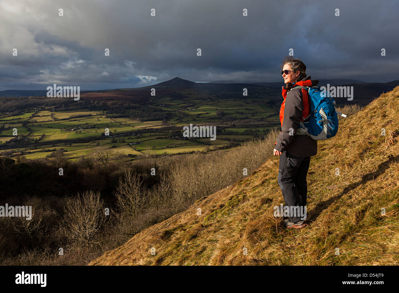 Escursionista femmina su pendii di The Skirrid con la montagna Sugar Loaf in distanza, Wales, Regno Unito Foto Stock