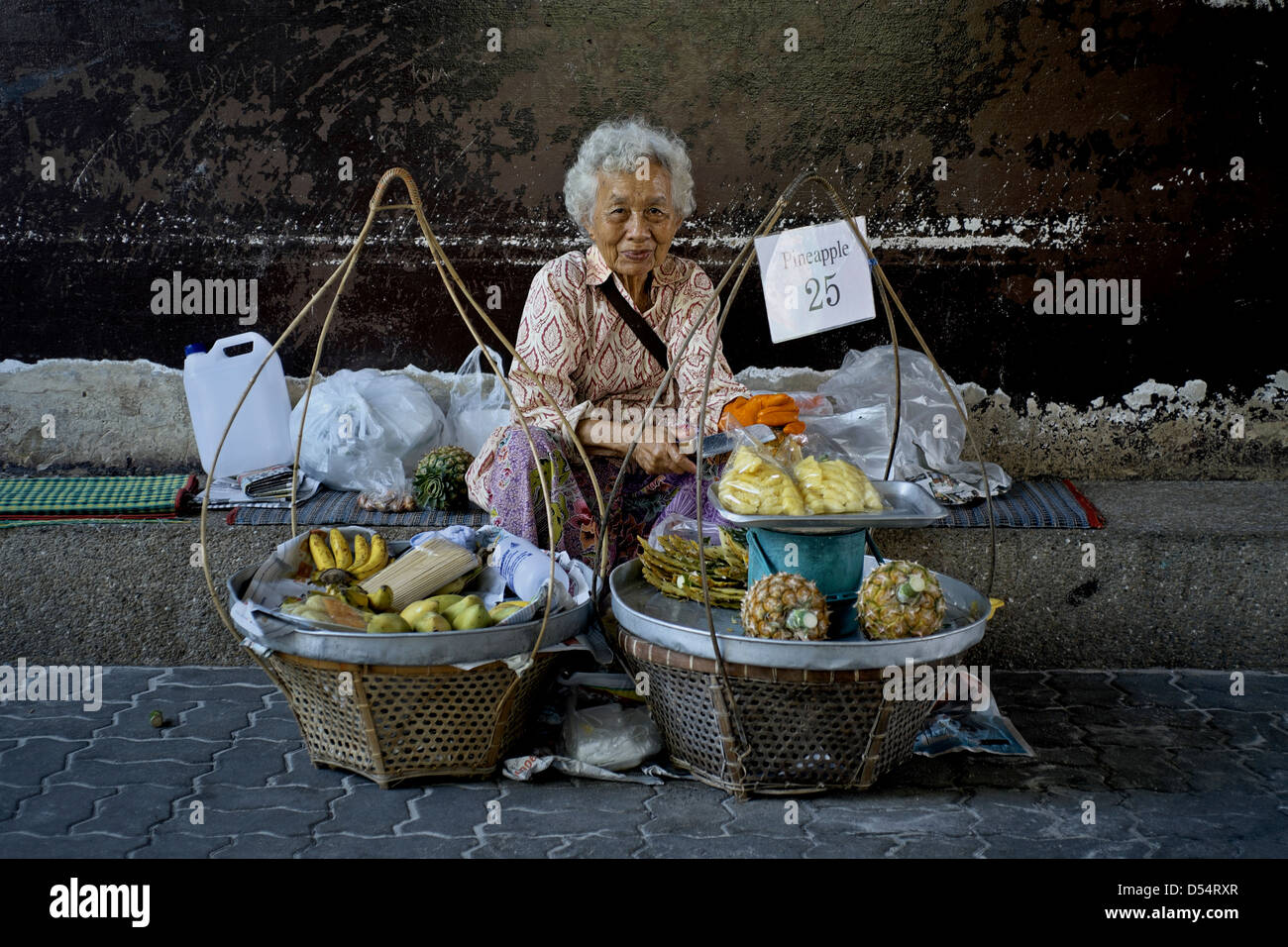 Fornitore di cibo di strada in Thailandia. Donna anziana che vende frutta. Thailandia S. E. Asia Foto Stock