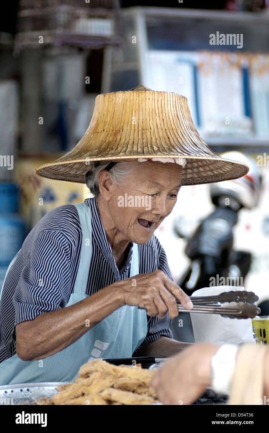 Un felice e ridere anziani Thailandia street fornitore di cibo che serve i clienti. Thailandia SUDEST ASIATICO Foto Stock