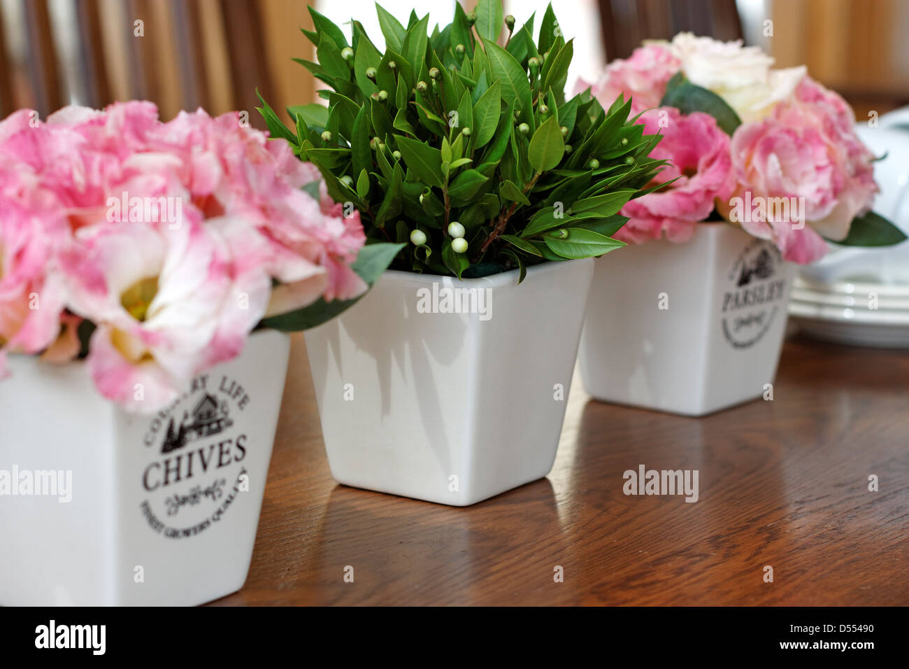 Lisianthus fiori e foglie di mirto e bacche di contenitori in ceramica su una tavola di legno Foto Stock