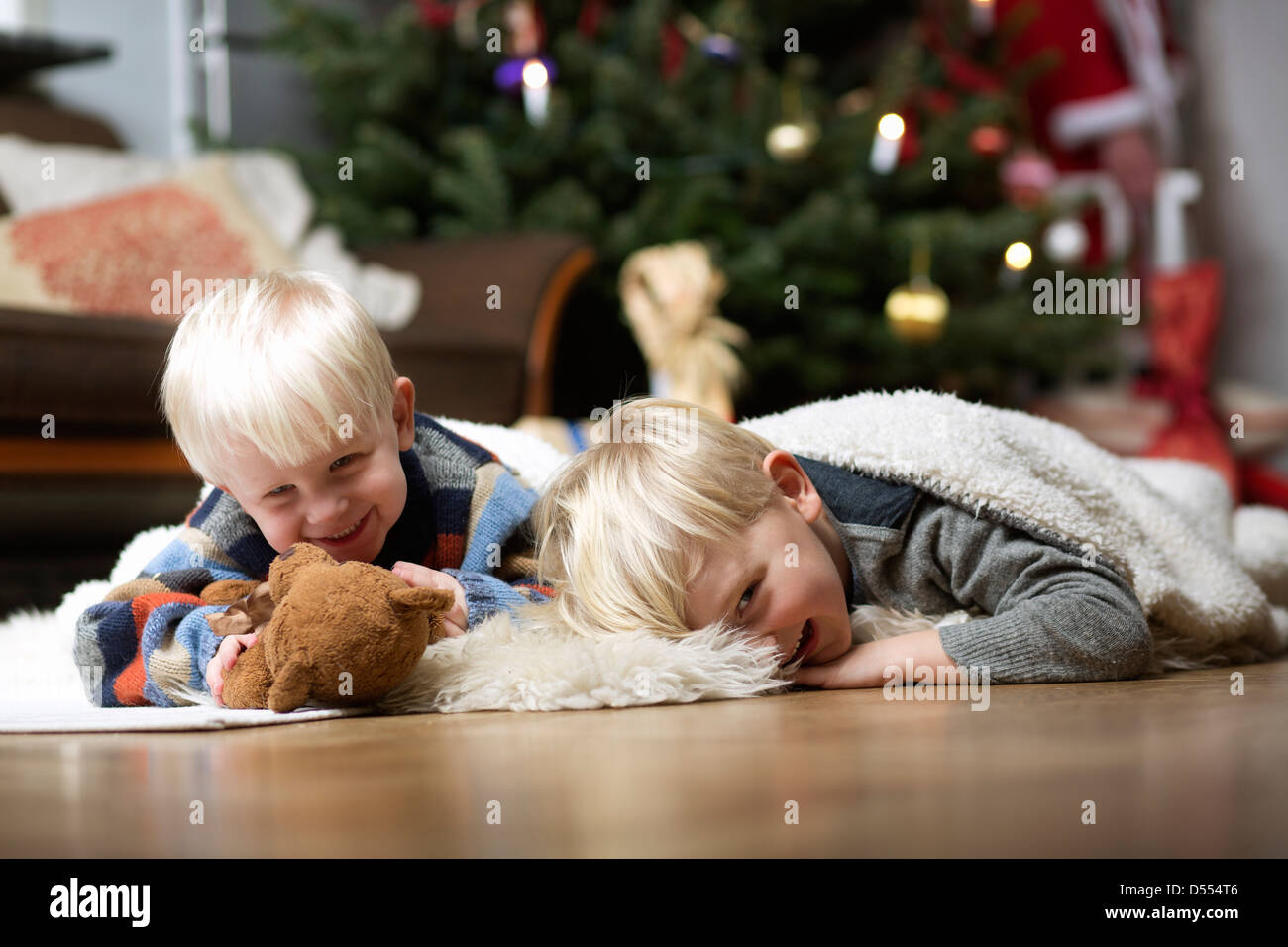 Ragazzi giocare sul pavimento per albero di Natale Foto Stock