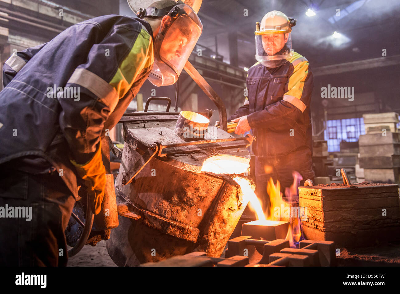 I lavoratori di colata di metallo fuso in fonderia Foto Stock