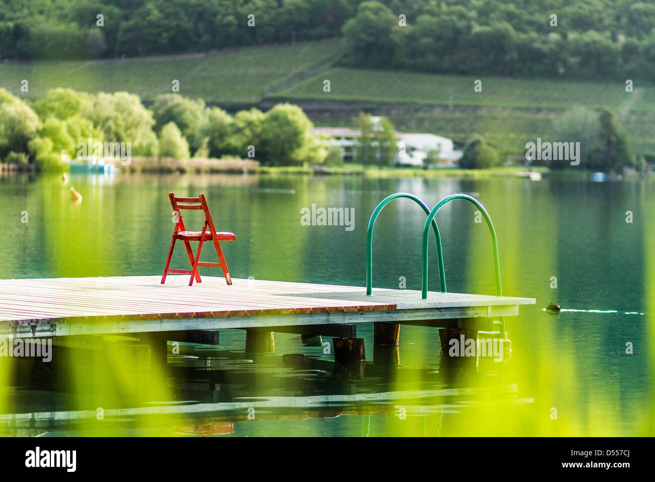 Sedia sul molo in legno ancora in lago rurale Foto Stock