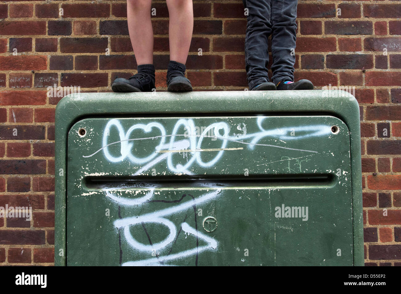 I bambini giocano sulla sommità del verde scatola di giunzione sulla hight street Foto Stock