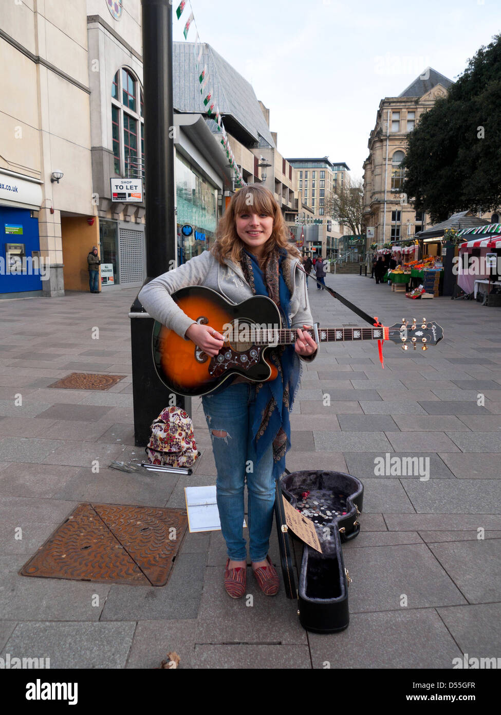 Giovane attraente busker Sophie che suona la sua chitarra su un Cardiff City Centre Street Galles Gran Bretagna Regno Unito KATHY DEWITT Foto Stock