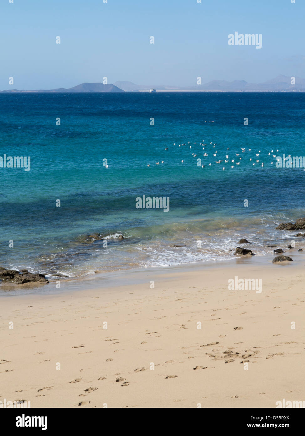 Playa Blanca Harbour Beach, Lanzarote con Fuerteventura Armas ferry all'orizzonte Foto Stock