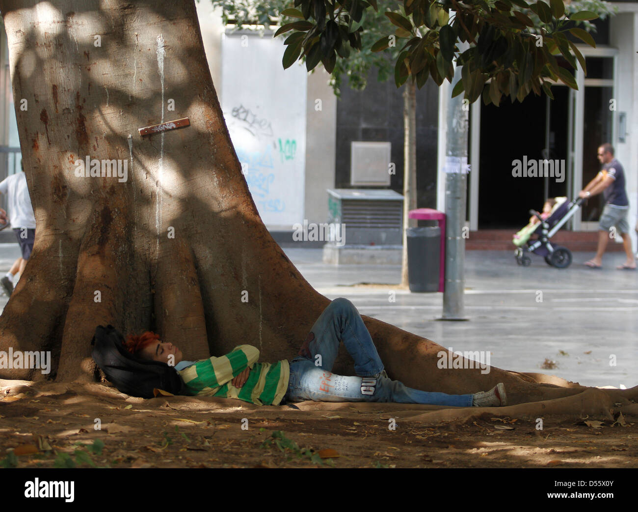 Un giovane uomo riposa sotto un albero di Palma de Mallorca la piazza centrale Foto Stock