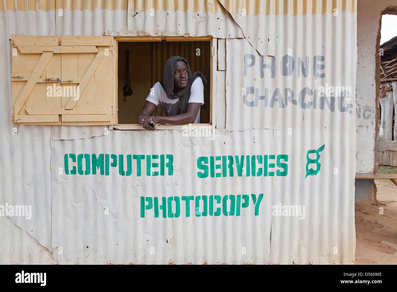 Uomo in attesa di business in un telefono mobile stand di ricarica, Yala, Kenya. Foto Stock