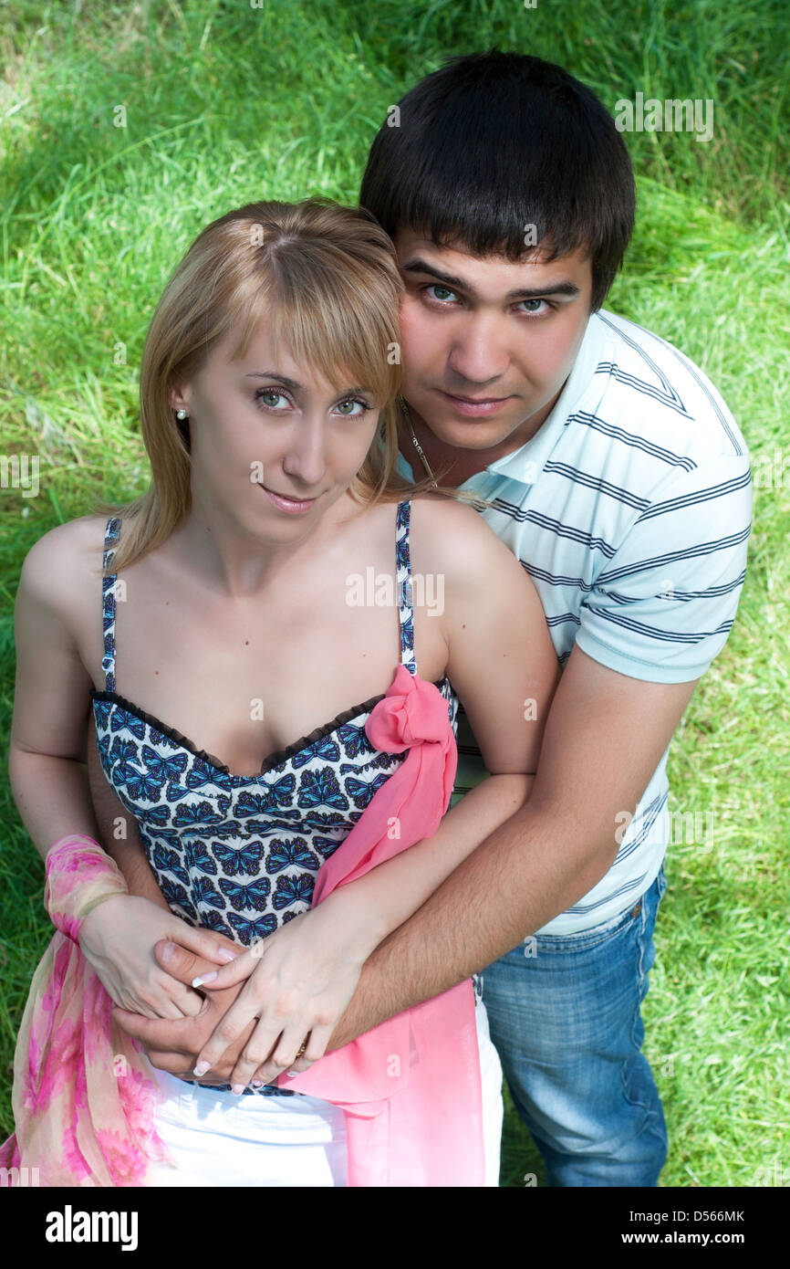 Il giovane uomo abbraccia la ragazza in primavera all'aperto tra il fogliame verde Foto Stock