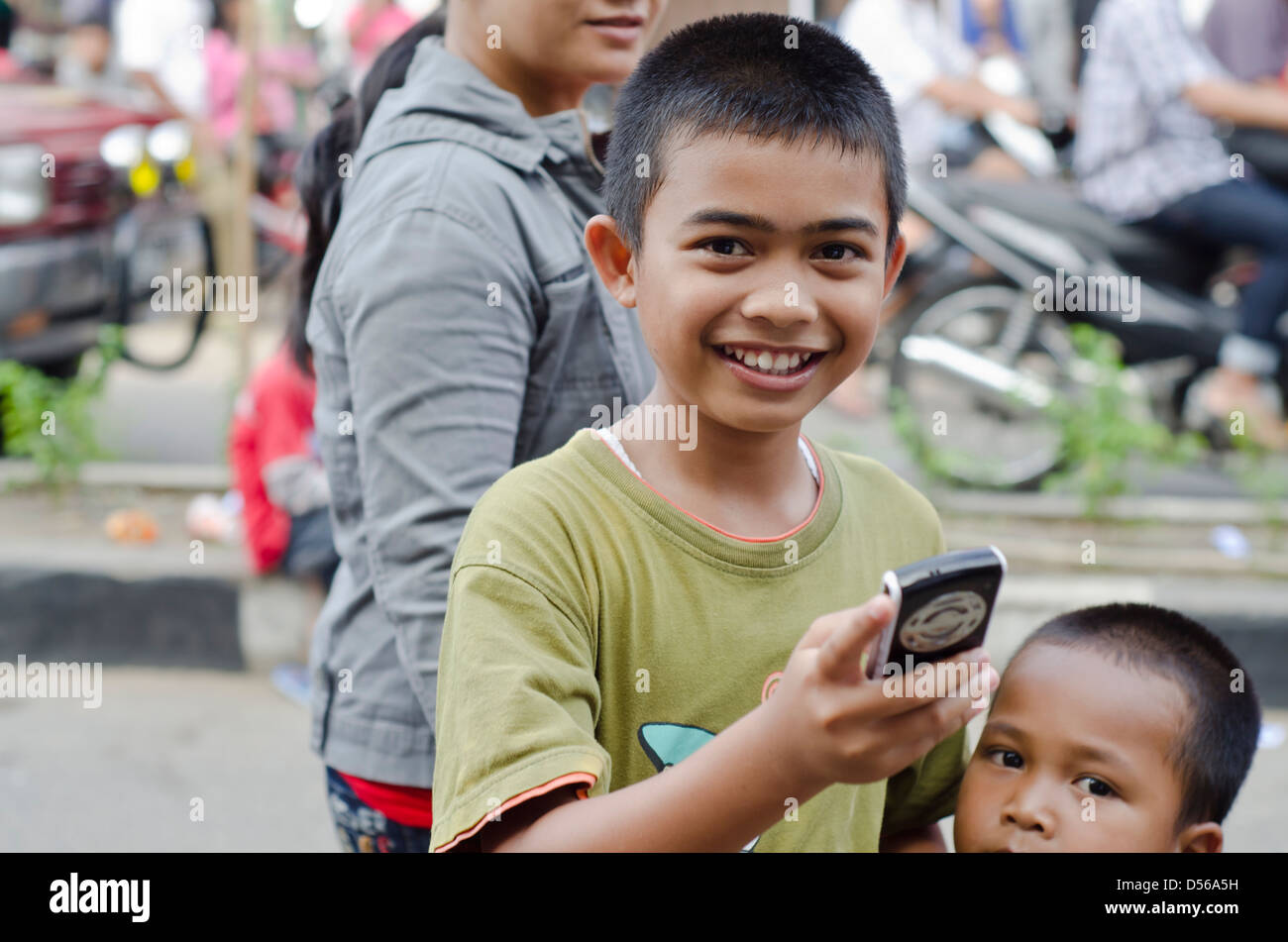 Sorridente ragazzo indonesiano con il telefono cellulare Foto Stock