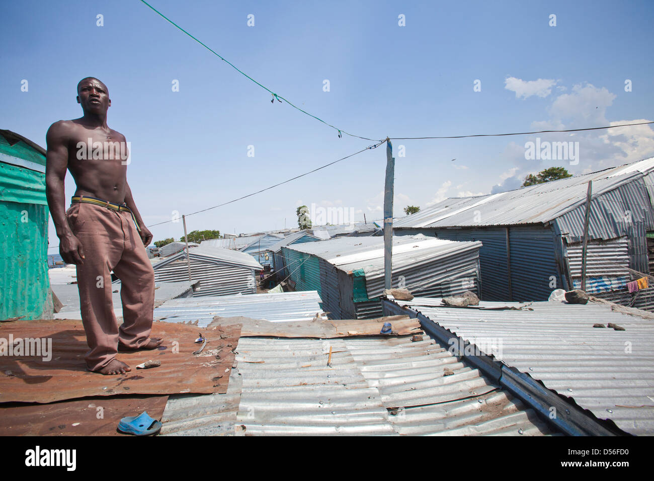 Uomo in piedi sul tetto ondulato in baraccopoli, Remba Island, il lago Victoria, in Kenya. Foto Stock