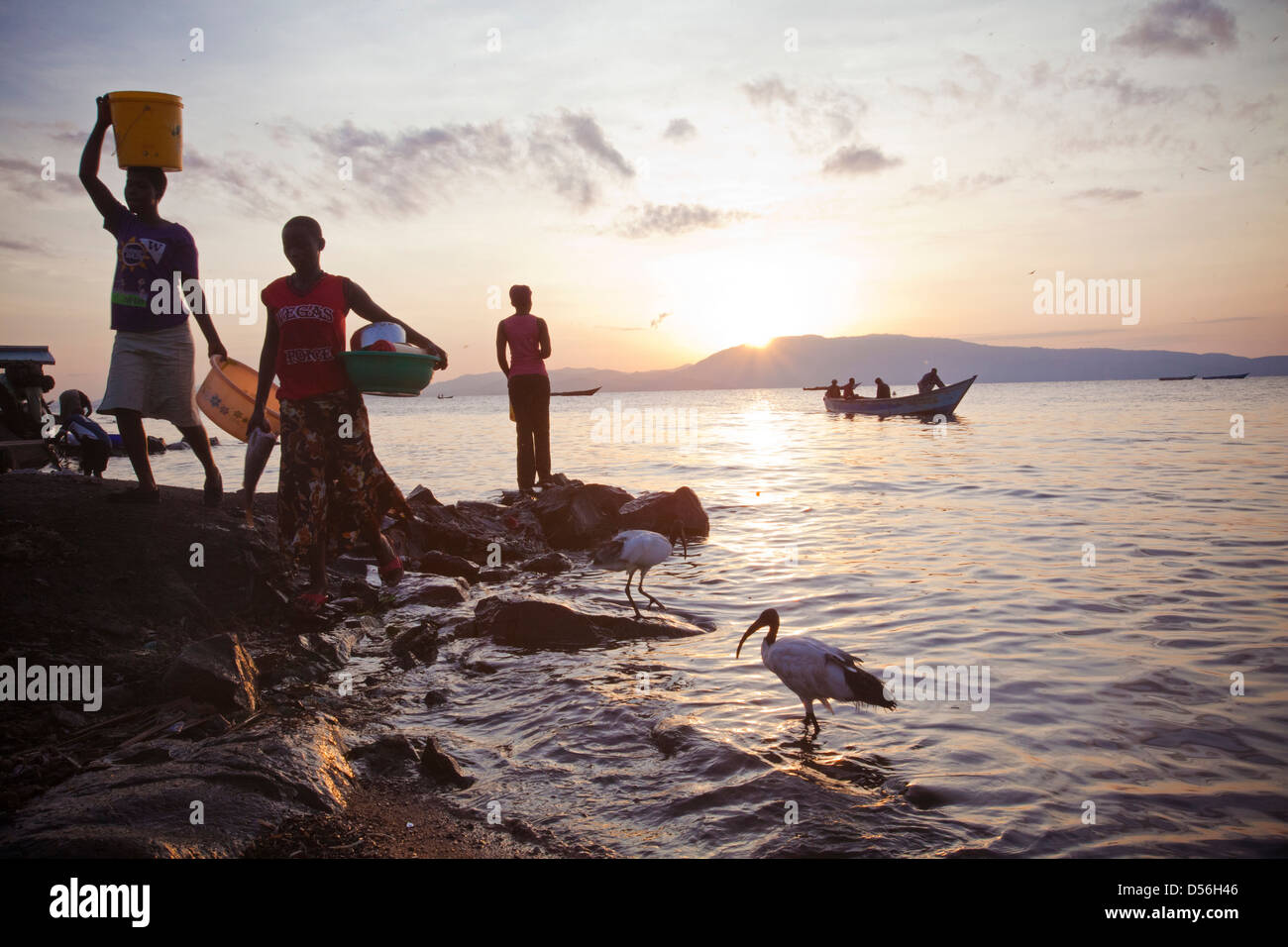 Le donne a sunrise tornando dalla pulizia di pentole e tegami, Remba Island, il lago Victoria, in Kenya. Foto Stock